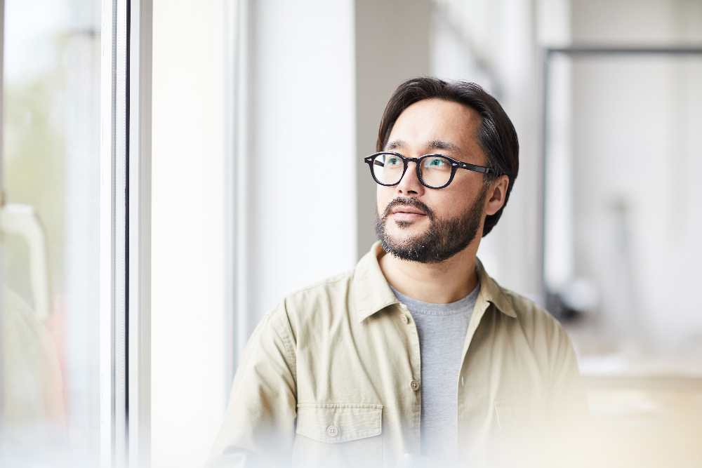 asian man staring out window