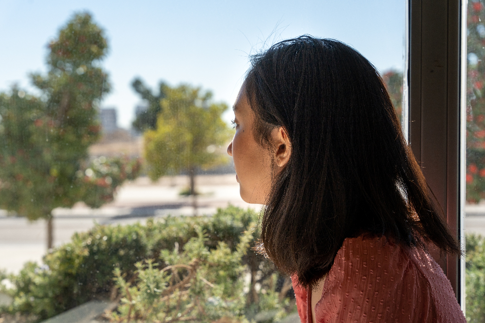 young woman looking out window