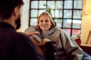 Two adults sitting together in a warm room having a supportive conversation