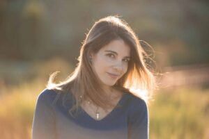 An adult stands calmly outdoors in warm golden light