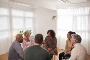 A group of adults sits in a circle during a supportive group therapy session