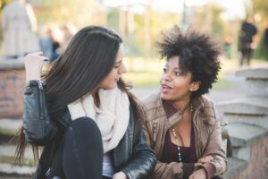 Two adults sit together outdoors in warm conversation