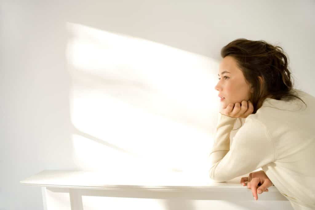 An adult sits quietly in soft light, lost in thought