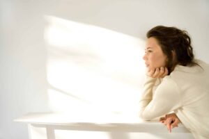 An adult sits quietly in soft light, lost in thought