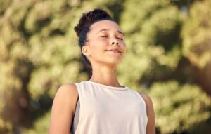 An adult breathes calmly with eyes closed in soft outdoor light