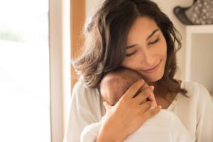 A parent gently cradles a newborn in soft, warm light