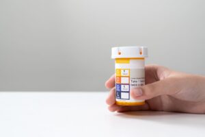 A hand holds a prescription medication bottle
