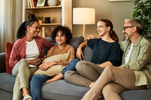 A family sits together on a sofa in warm conversation