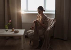 Woman knitting calmly in soft, warm sunlight at home