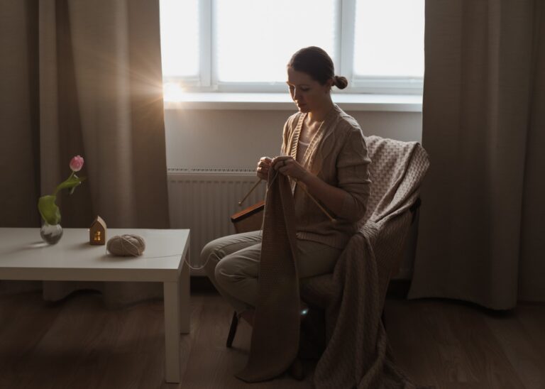 Woman knitting calmly in soft, warm sunlight at home