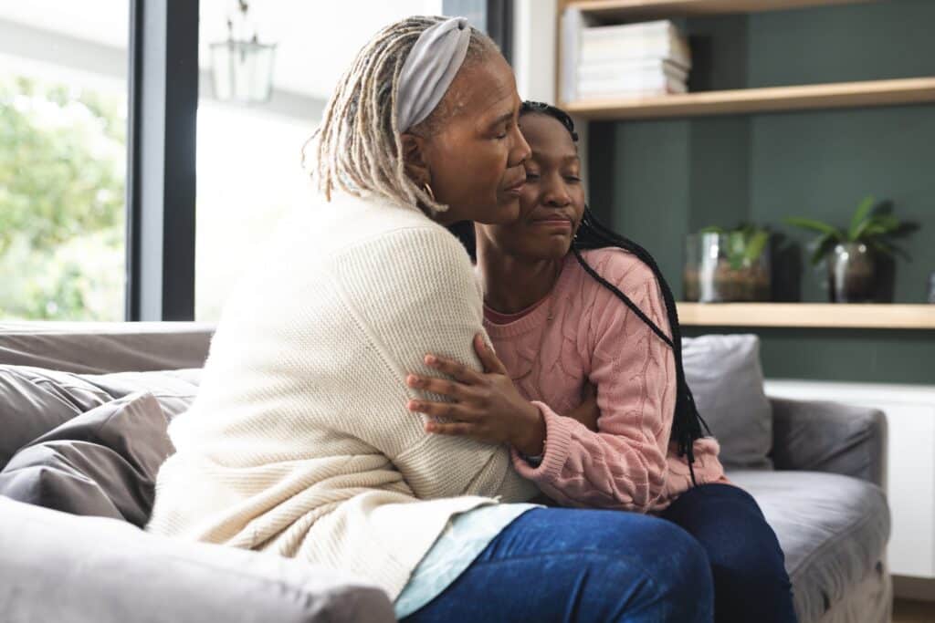 A woman warmly embracing a younger family member on a sofa at home