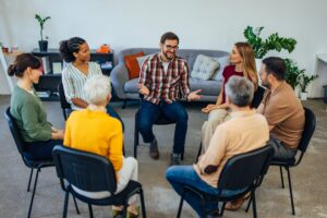 Adults sitting in a circle during a support group therapy session