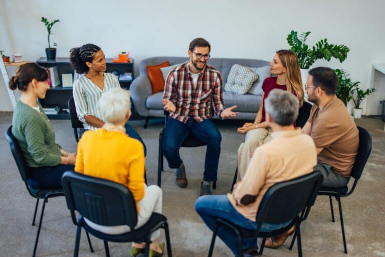 Adults sitting in a circle during a support group therapy session