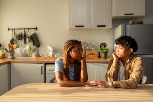 Two people having a serious, caring conversation at a kitchen table