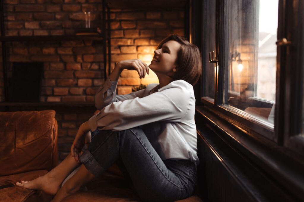 A woman sitting calmly by a window in warm evening light
