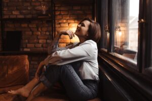 A woman sitting calmly by a window in warm evening light