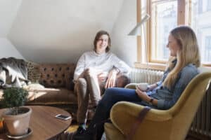 Two people having a supportive conversation in a warm, bright room