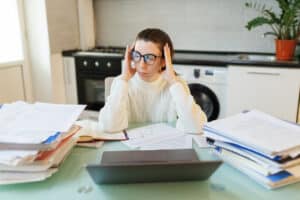Adult overwhelmed by paperwork at a home desk